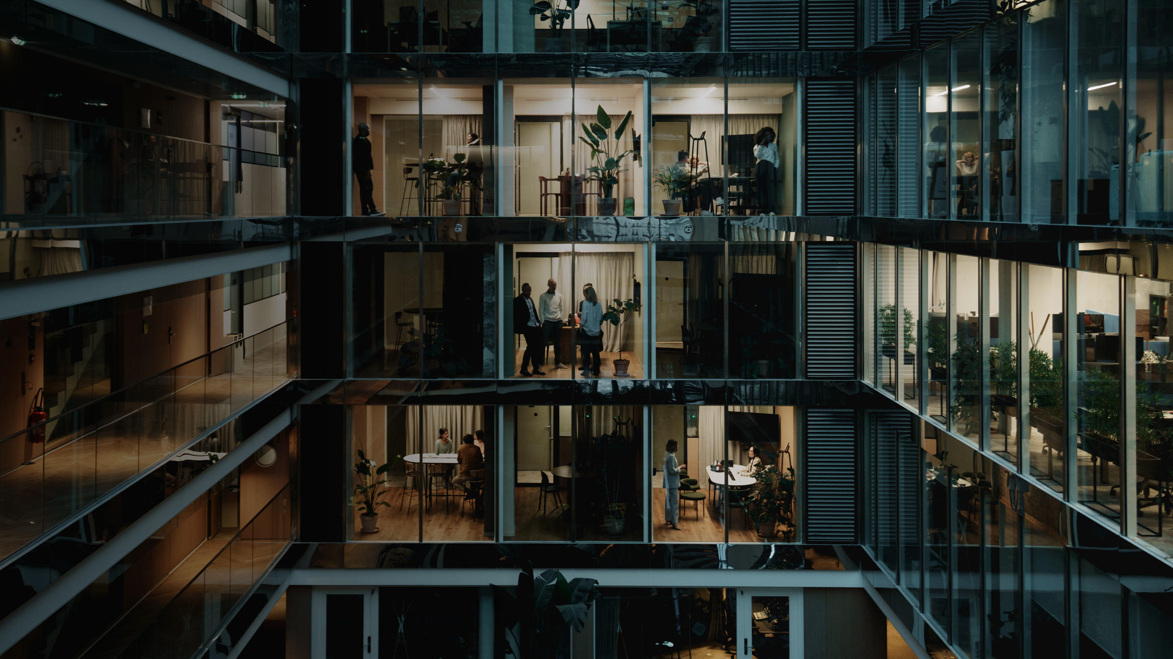 large view outside looking in on office workers in multi-story office building